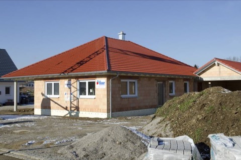 Rohbau eines Bungalows mit rotem Dach im Neubaugebiet