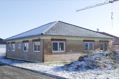 Fertig eingedeckter Bungalow mit grauem Walmdach im Schnee