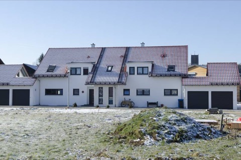 Fertig gestellte Hauszeile mit weißen Fassaden und Ziegeldach