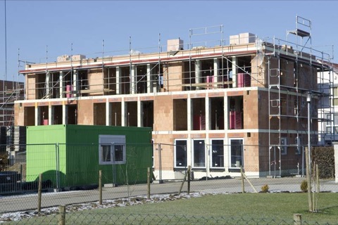 Rohbau eines Mehrfamilienhauses aus Porotherm-Ziegeln mit Baugerüst und grünem Container