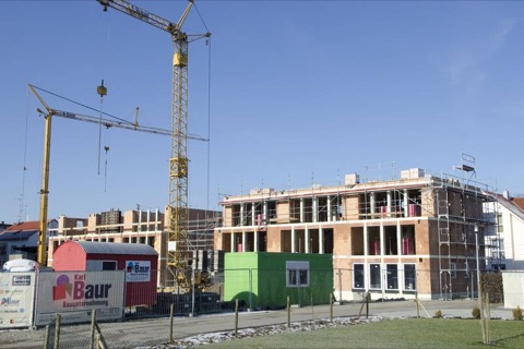 Rohbau des Mehrfamilienhauses mit zwei Turmdrehkränen und Baur-Baustellenschild
